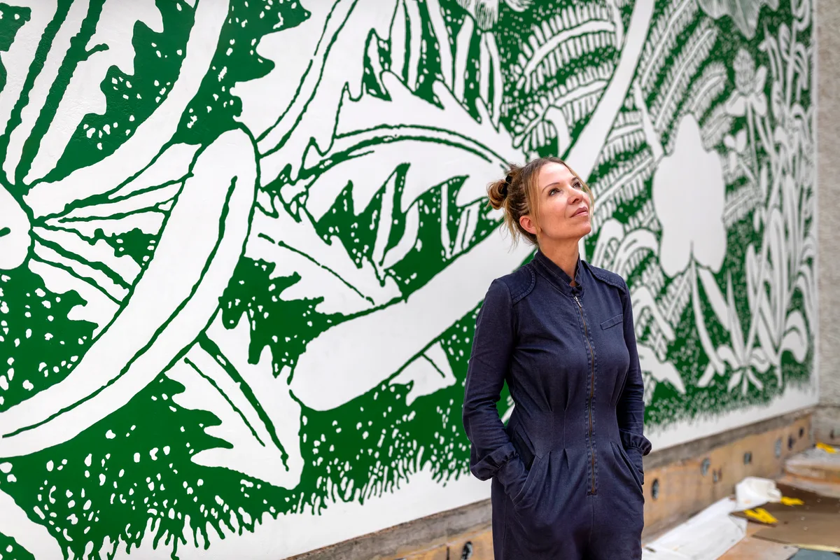 Karoline Schreiber steht vor ihrem Werk International Landscapes, einem grünen und weissen Wandbild.